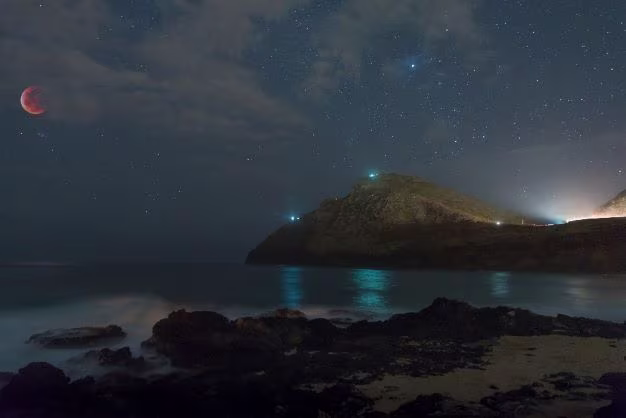 Gorgeous nighttime panorama of the Milky Way glowing above the Pacific ocean, mountains in the distance, Maui, Hawaii. 