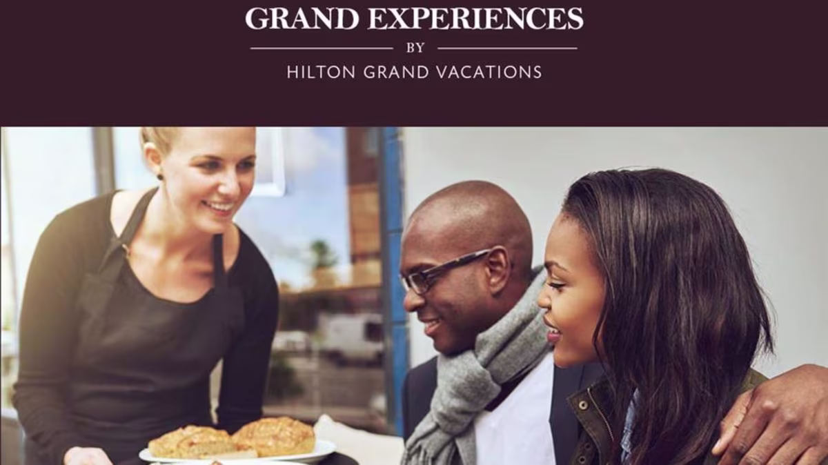 Waitress serving a couple dining out with the Hilton Grand Vacations Grand Experiences card.