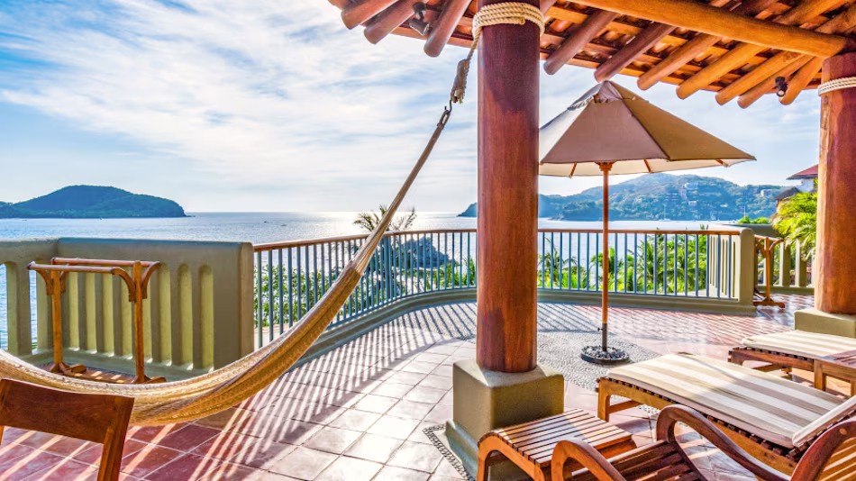 Tropical balcony looking off to sea, with hammock and sun umbrella and recliners.