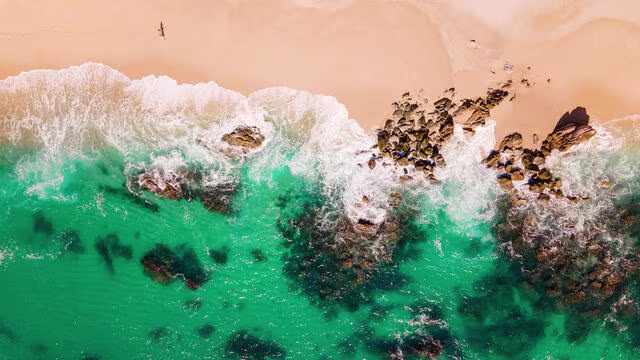 Aerial shot of the Sea of Cortez washing ashore a golden Los Cabos beach, Mexico. 