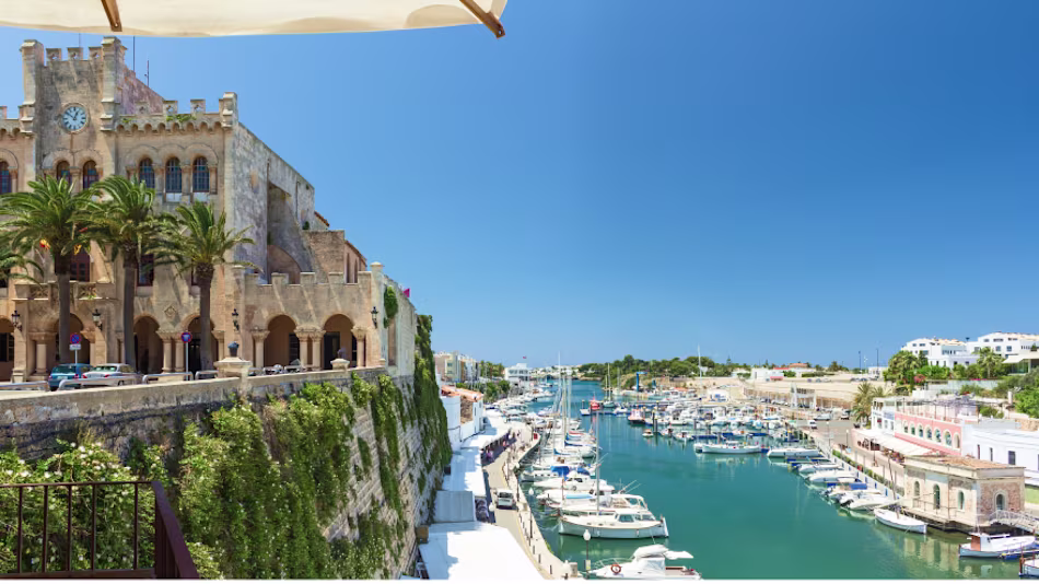 European castle overlooking the harbor with ships.