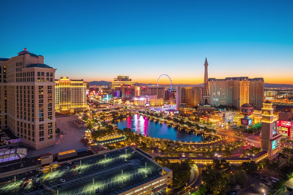 Las Vegas cityscape, glittering in the late sunset lights, with familiar hotels featured in the picture.