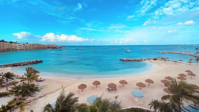 Palm trees and umbrellas on the beach of Simpson Bay in St. Maarten