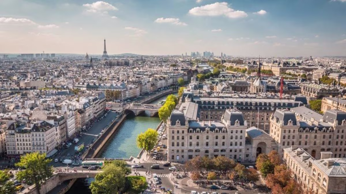 Stunning aerial shot, Paris cityscape, Seine River, clear blue skies overhead.