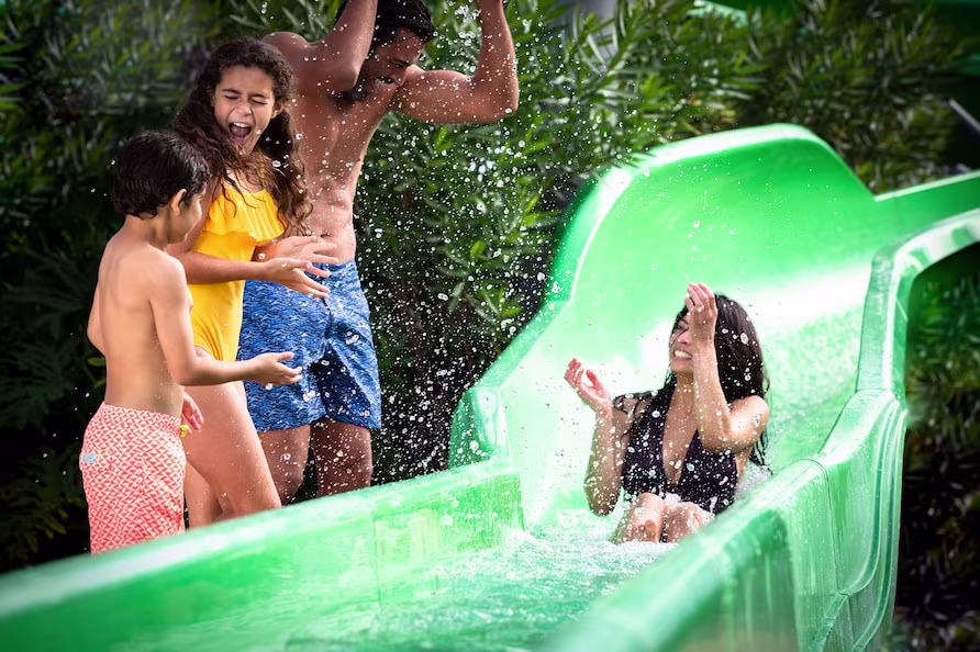 Happy family enjoying the waterslide at a Hilton Grand Vacations Orlando, Florida resort. 