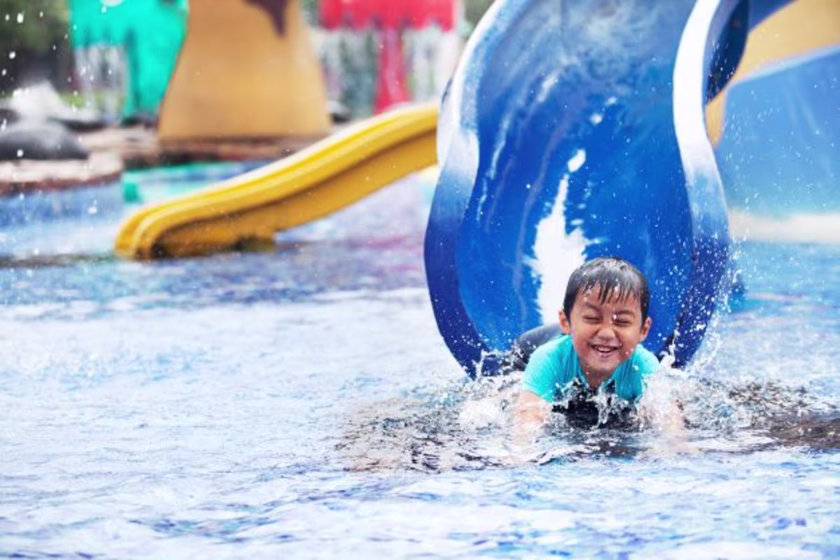Little boy laughing coming down waterslide.