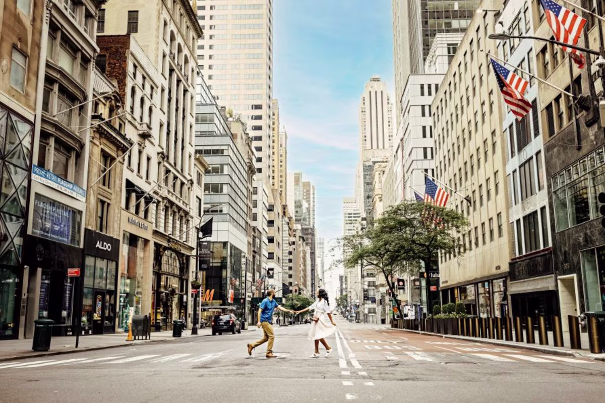 Couple walking, hand in hand, empty urban street, blue skies peek through buildings, New York, New York.