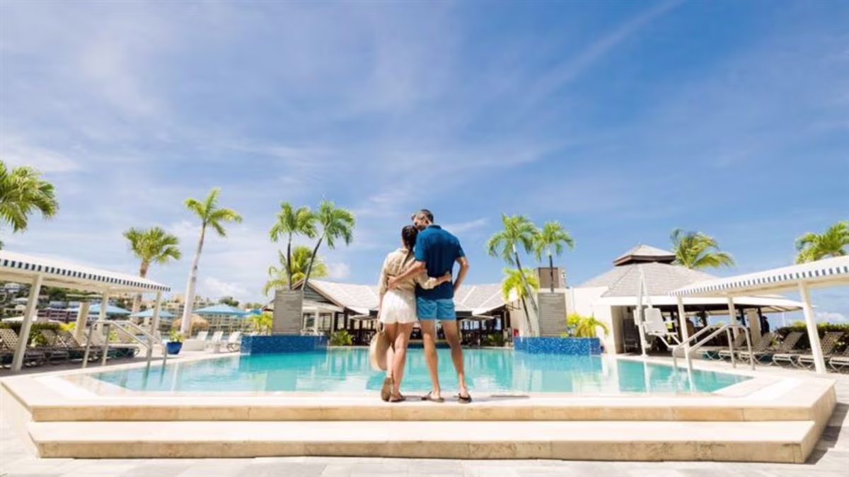 A couple stands together at the pool at Royal Palm, a Hilton Vacation Club in Sint Maarten in the Caribbean
