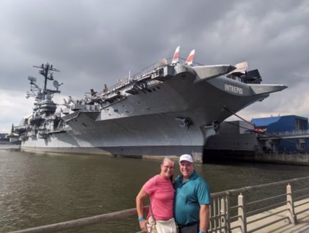 Two Hilton Grand Vacations Members in front of the battleship Intrepid in New York